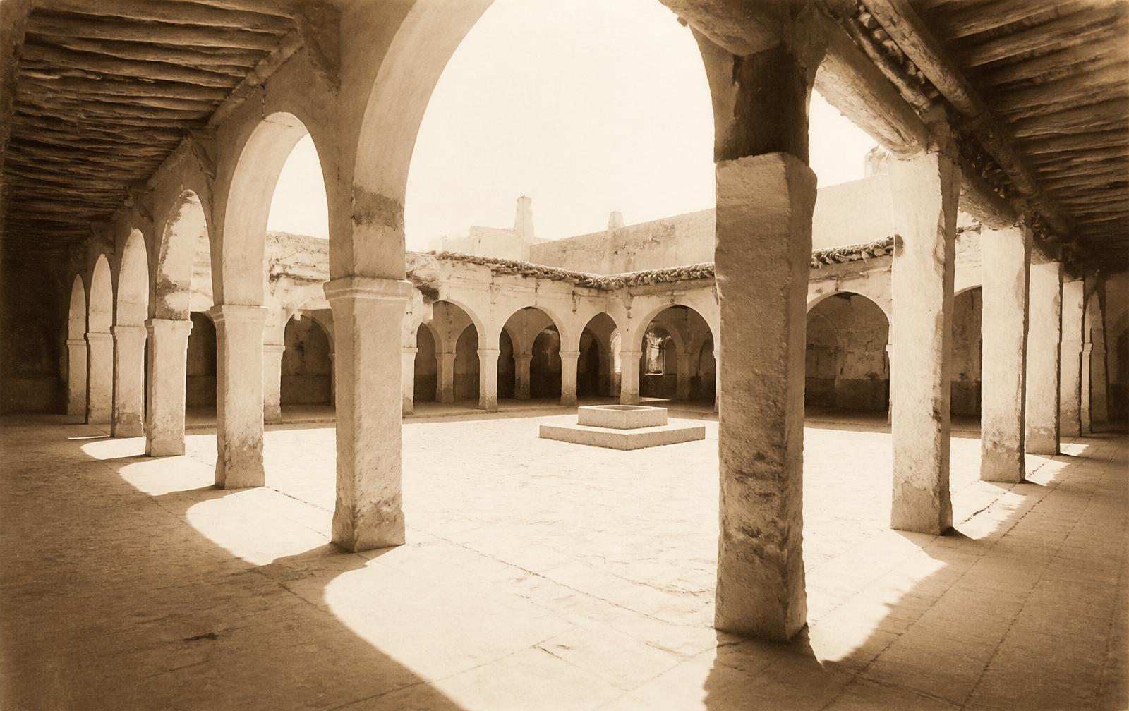 Sepia photograph of the arcaded market square of Beni Isguen, empty and bathed in Saharan light.