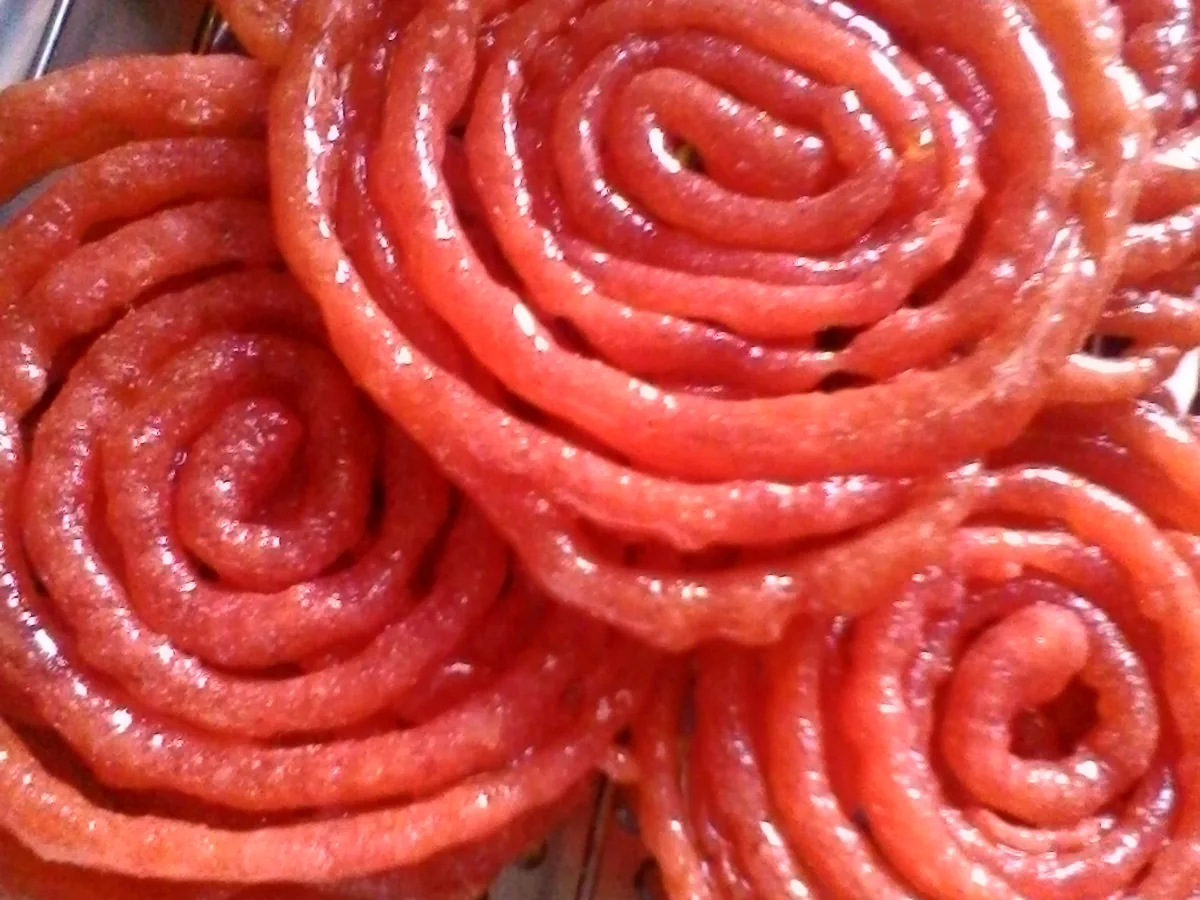 Bright golden spiral-shaped Algerian Zlabia coated in syrup.